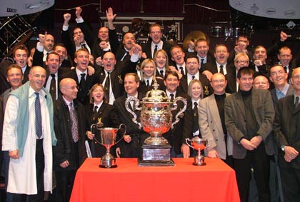 Members of Black Dyke celebrate with man in bizarre white coat [and the trophy]